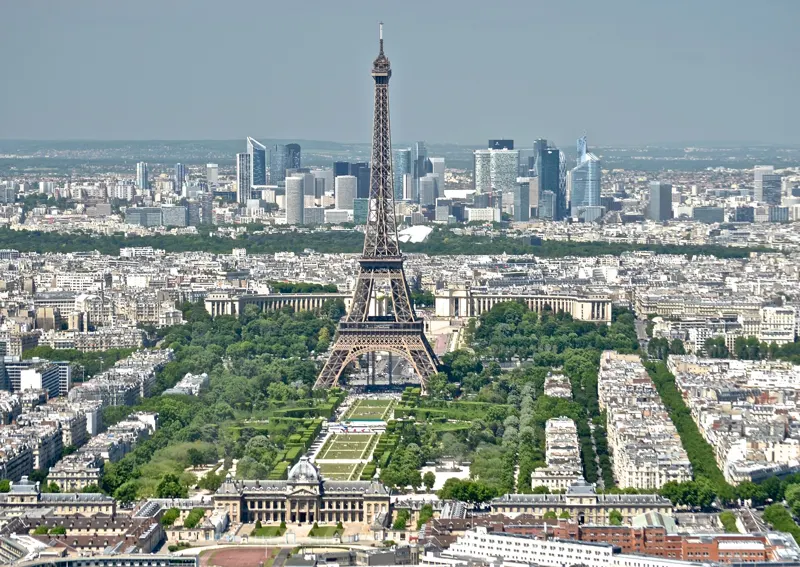 The Eiffel Tower and the Champ de Mars seen from above, with La Defense skyscrapers in the distance